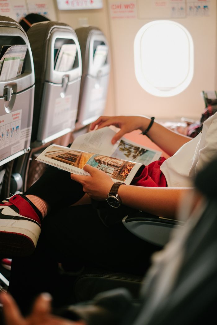 best-selling product-01 Person reading a magazine while seated in an airplane, offering an in-flight experience.