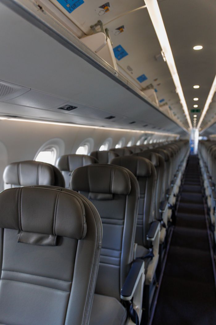 best-selling product-02 Interior view of an empty airplane cabin featuring rows of leather seats and overhead compartments.