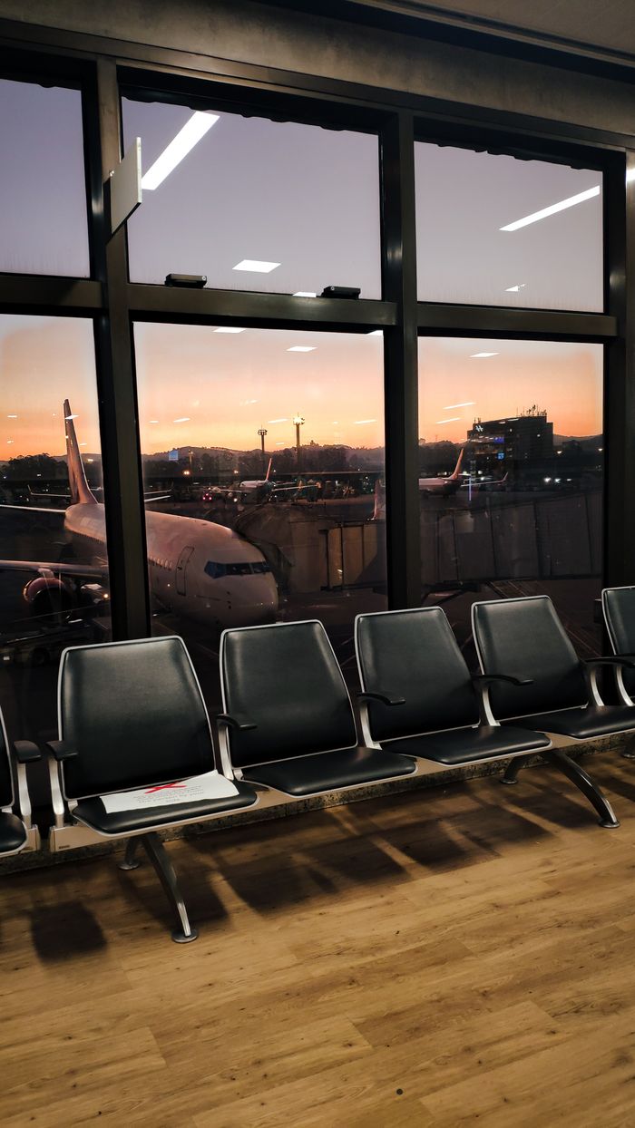 Crafting Captivating Headlines: Your awesome post title goes here View of empty airport seating area with airplanes outside at sunset.